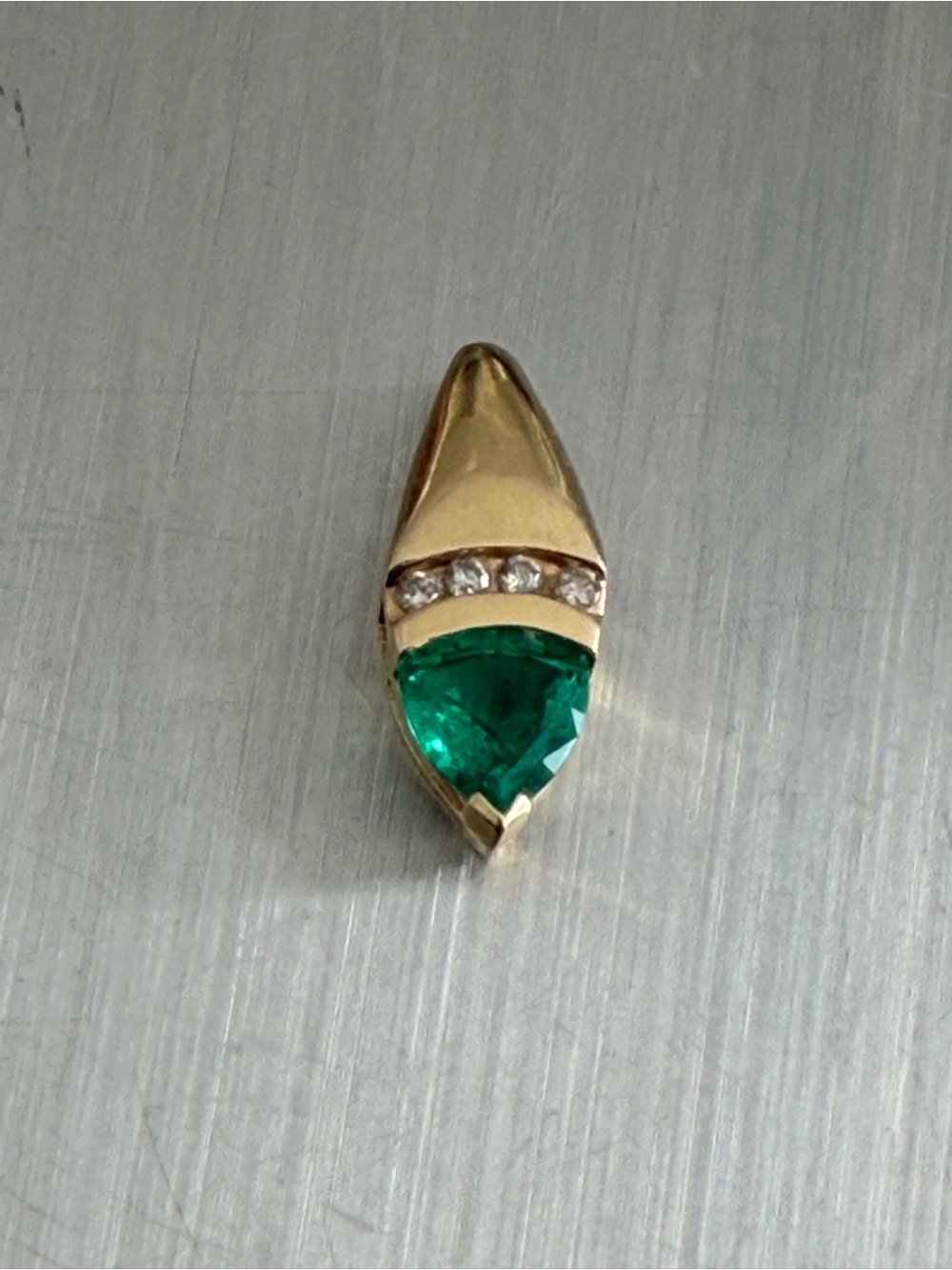 Vintage Trillion-cut, vibrant Emerald set in a V-prong at the tip.